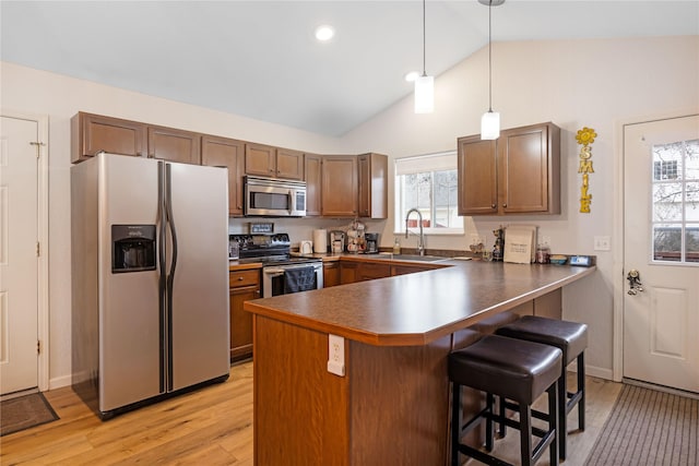 3817 Concord Dr, Missoula, MT 59808 - kitchen with a peninsula, a kitchen bar, a sink, appliances with stainless steel finishes, and vaulted ceiling