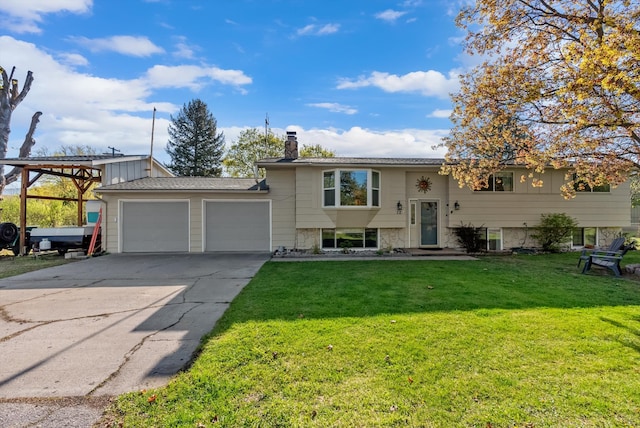 raised ranch featuring an attached garage, driveway, a chimney, and a front lawn