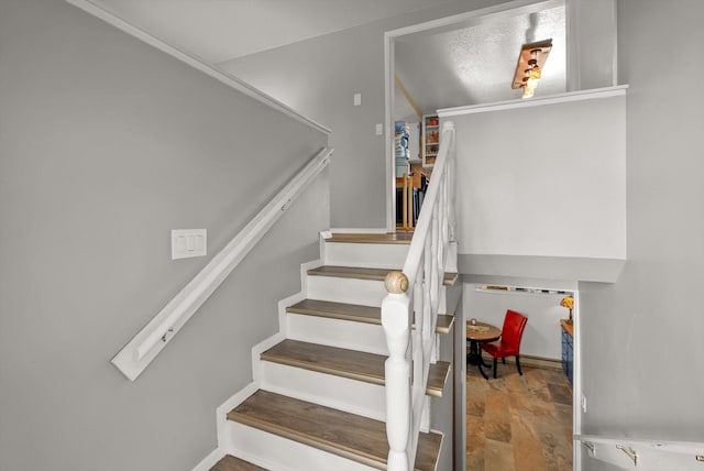 stairway featuring baseboards and stone finish flooring