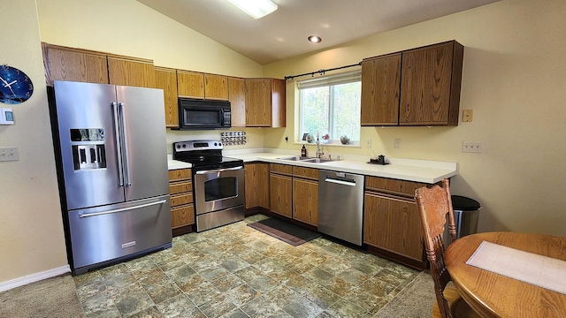 kitchen with a sink, vaulted ceiling, light countertops, and appliances with stainless steel finishes