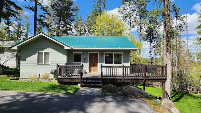view of front of house with metal roof, a deck, and a front yard