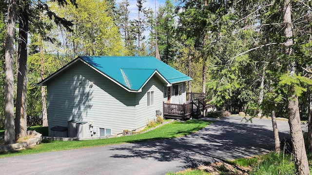 view of property exterior with a deck, aphalt driveway, and metal roof
