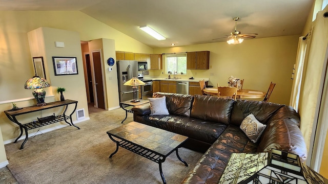 living area with visible vents, lofted ceiling, ceiling fan, and light carpet