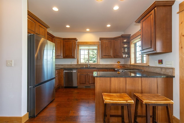 kitchen with a sink, a peninsula, stainless steel appliances, and recessed lighting