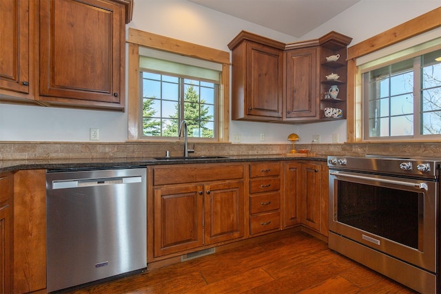 kitchen featuring visible vents, a sink, open shelves, brown cabinets, and stainless steel appliances