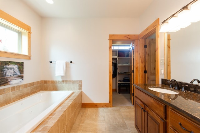 full bathroom with tile patterned floors, a bath, baseboards, vanity, and a spacious closet