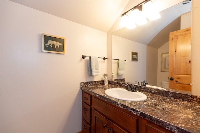 half bathroom with vanity, toilet, vaulted ceiling, and visible vents