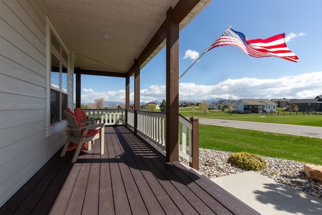 wooden deck with a yard, covered porch, and a residential view