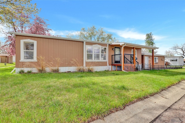 manufactured / mobile home with a front lawn, covered porch, and fence