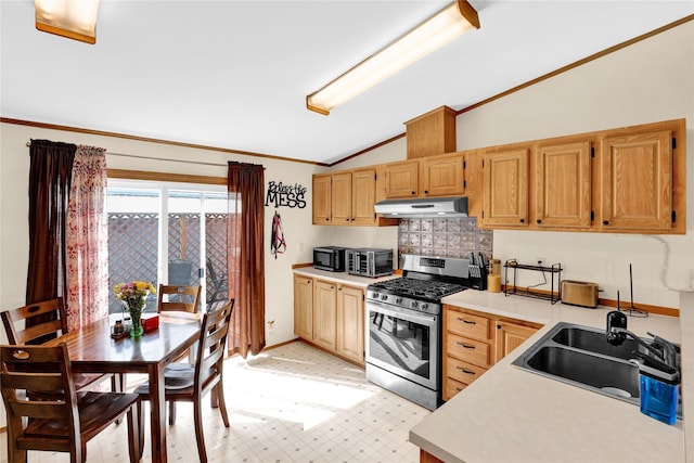 kitchen featuring stainless steel gas range, a sink, light floors, light countertops, and vaulted ceiling