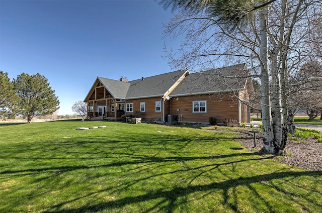 406 Back Nine Ln, Hamilton, MT 59840 - rear view of house with central air condition unit, a shingled roof, a chimney, and a lawn