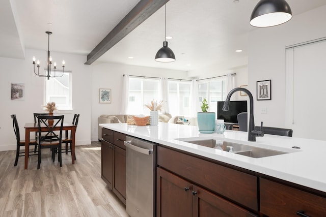 kitchen with a sink, light countertops, open floor plan, and stainless steel dishwasher