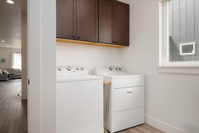 clothes washing area with cabinet space, recessed lighting, light wood finished floors, washing machine and dryer, and baseboards