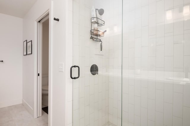 bathroom featuring a stall shower, baseboards, tile patterned floors, and toilet