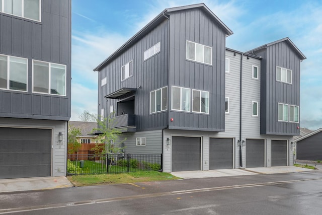 view of front facade featuring fence, an attached garage, and board and batten siding