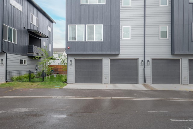 exterior space featuring an attached garage, board and batten siding, and fence