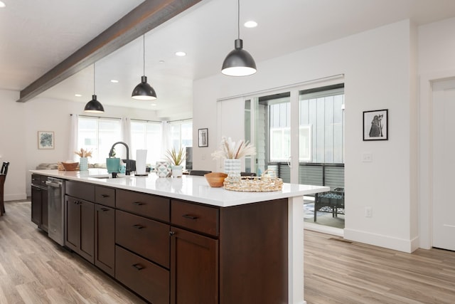 kitchen with a sink, light wood-style flooring, baseboards, and light countertops