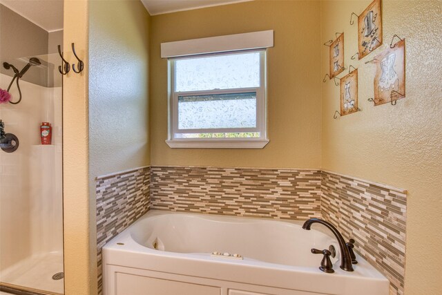 bathroom with a stall shower, a textured wall, and a bath