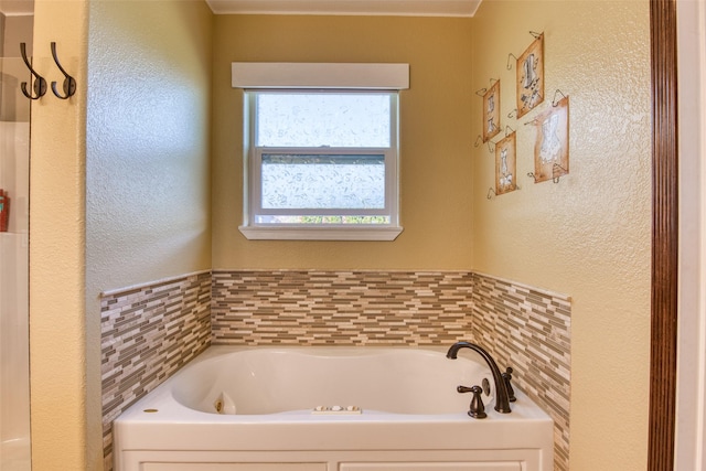 bathroom with a bath and a textured wall