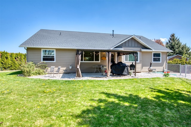 back of house with a yard, roof with shingles, fence, and a patio