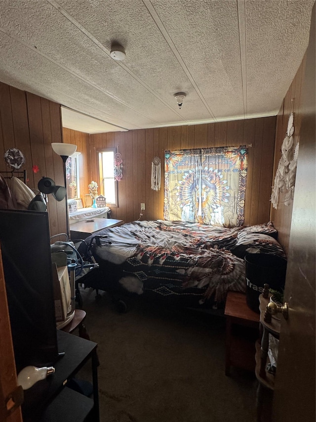 bedroom with wood walls, carpet, and a textured ceiling