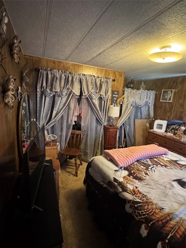 bedroom with carpet flooring, a textured ceiling, and wooden walls
