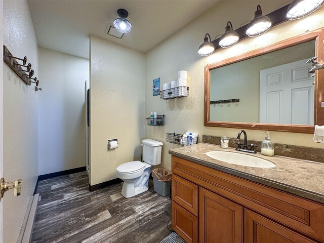 101 11th Ave N, Shelby, MT 59474 - bathroom featuring vanity, toilet, baseboards, and wood finished floors