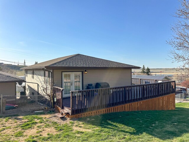 101 11th Ave N, Shelby, MT 59474 - rear view of property with french doors, fence, a deck, a lawn, and roof with shingles