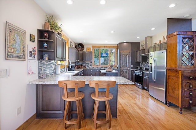 34426 Ridge Rd, Polson, MT 59860 - kitchen featuring stainless steel appliances, a peninsula, a sink, light wood-style floors, and tasteful backsplash