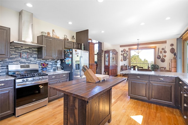 34426 Ridge Rd, Polson, MT 59860 - kitchen with appliances with stainless steel finishes, wall chimney range hood, dark brown cabinetry, light wood finished floors, and wood counters