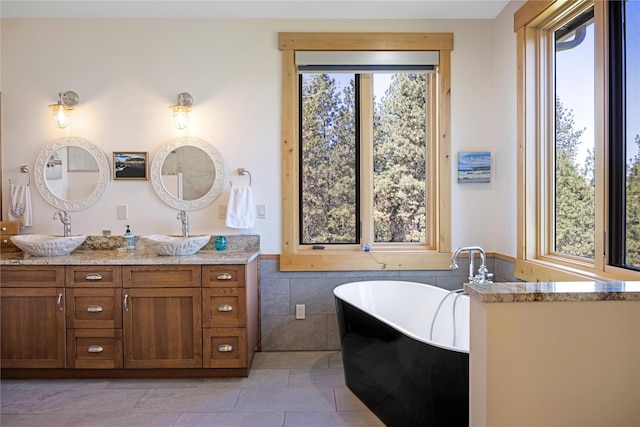 34426 Ridge Rd, Polson, MT 59860 - bathroom with healthy amount of natural light, double vanity, a freestanding bath, a wainscoted wall, and tile walls