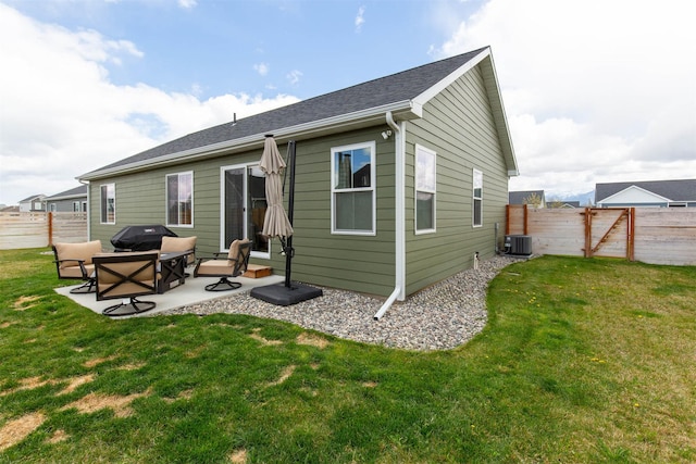 rear view of house with central air condition unit, a patio, a lawn, and a fenced backyard