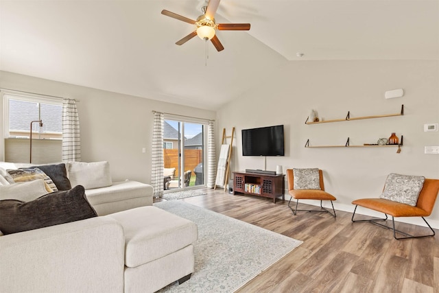 living room with a ceiling fan, vaulted ceiling, and wood finished floors