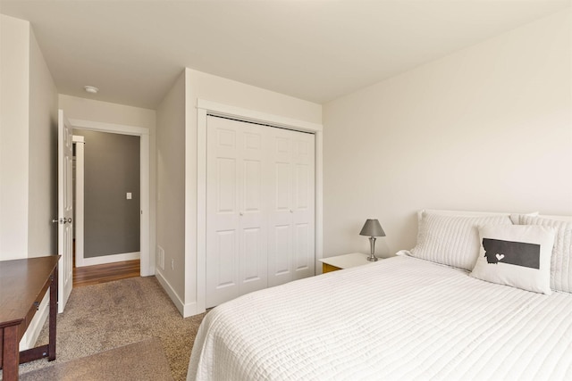 carpeted bedroom with a closet and baseboards