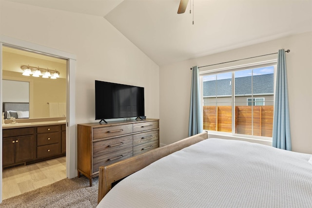 bedroom featuring connected bathroom, vaulted ceiling, a ceiling fan, and a sink
