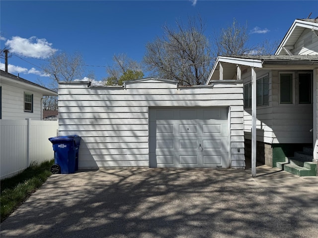 garage with aphalt driveway and fence