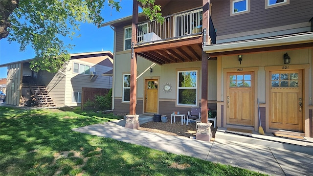 property entrance with a balcony and a lawn