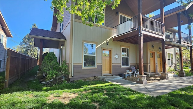 view of front of property with fence, a front lawn, and a balcony