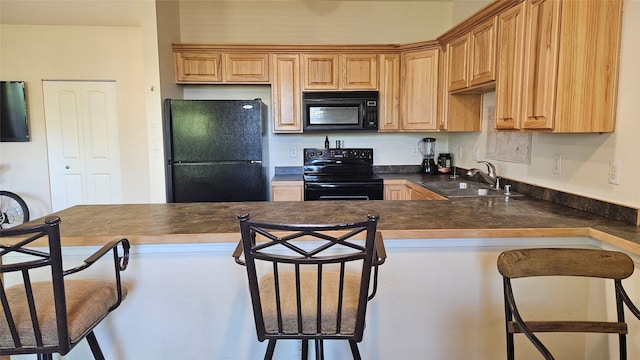 kitchen featuring a sink, a peninsula, black appliances, a breakfast bar area, and dark countertops
