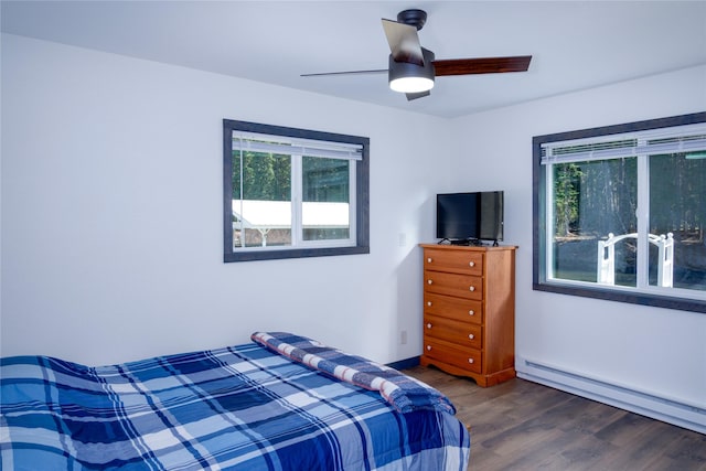 bedroom with a ceiling fan, multiple windows, a baseboard radiator, and wood finished floors