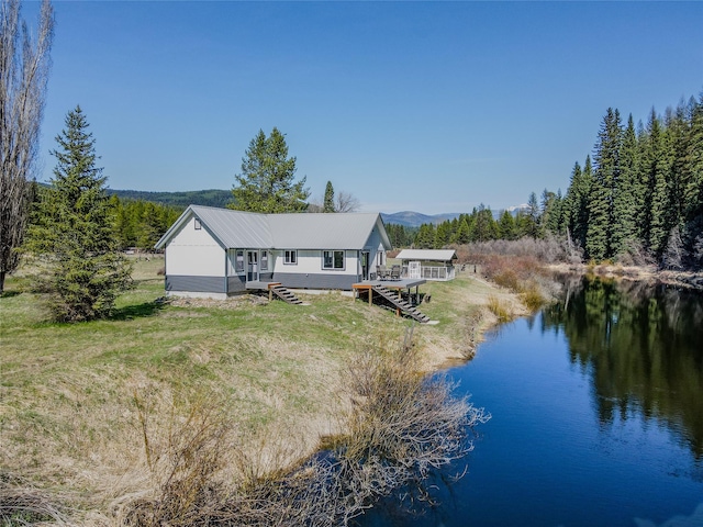 back of house featuring a lawn and a deck with water view
