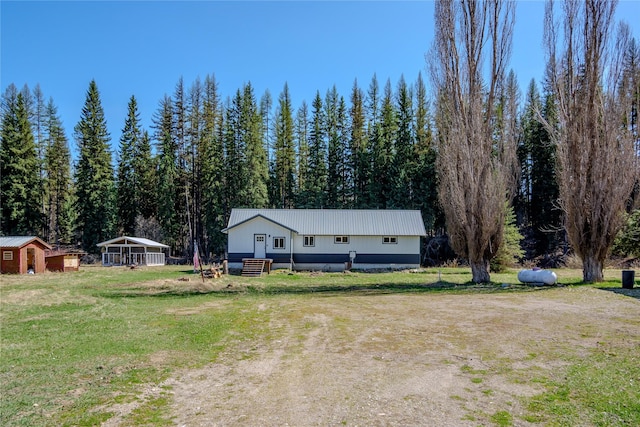 ranch-style house with a wooded view, an outdoor structure, and a front yard