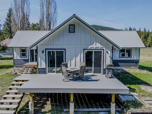back of house with metal roof, a wooden deck, and board and batten siding