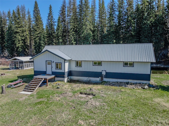 view of front facade featuring a front lawn, a forest view, and metal roof