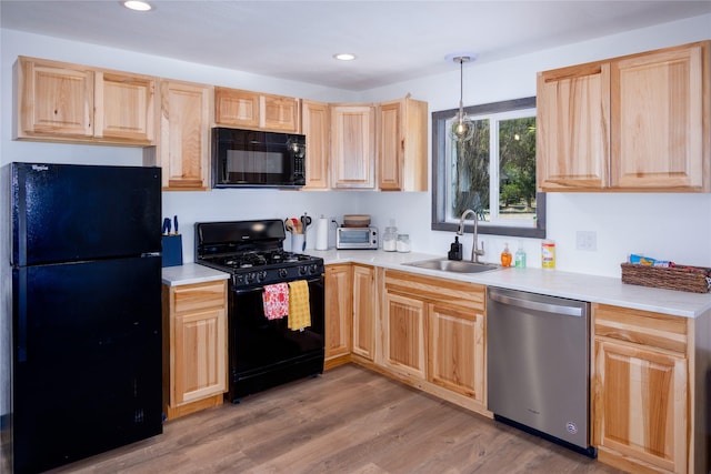 kitchen with a sink, light brown cabinets, light countertops, and black appliances