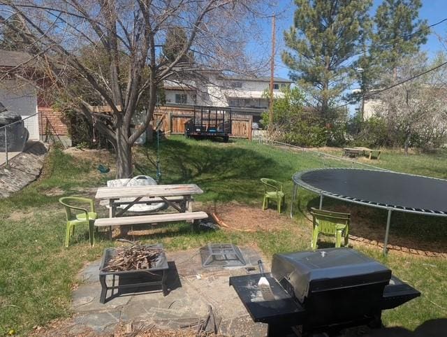 412 Raymond St, Helena, MT 59601 - view of grassy yard featuring a trampoline, a patio, and an outdoor fire pit