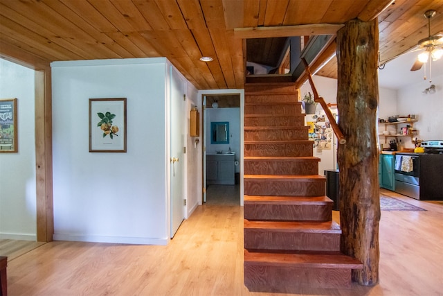 staircase featuring wooden ceiling, wood finished floors, baseboards, and ceiling fan