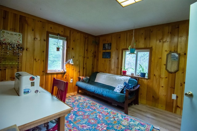 living area with plenty of natural light, wooden walls, and wood finished floors