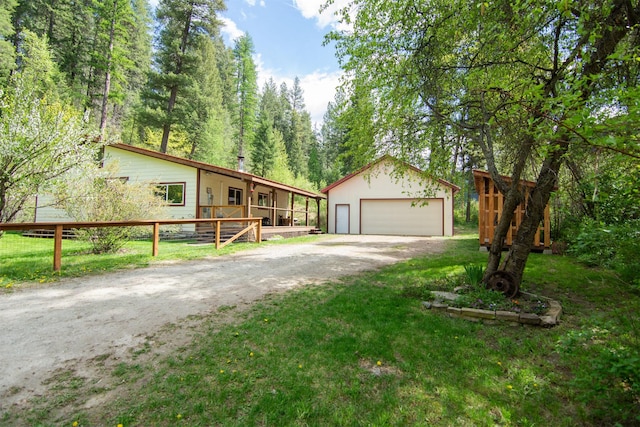 view of front of property featuring a front lawn, an outbuilding, a garage, and fence