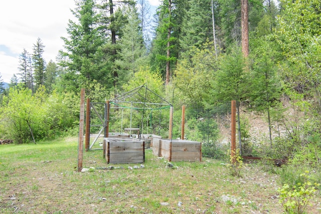view of yard with a wooded view and a vegetable garden